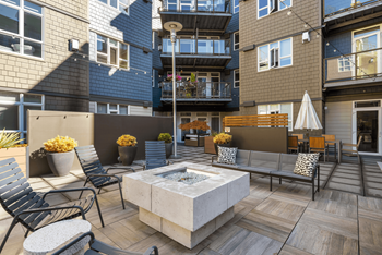 A patio with a fire pit and chairs.